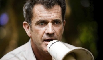 Mel Gibson shouts instructions into a megaphone on the set of the film Apocalypto