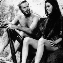 Charlton Heston e Linda Harrison seduti fianco a fianco in una scena de Il pianeta delle scimmie