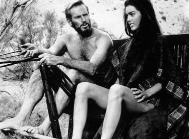 Charlton Heston e Linda Harrison seduti fianco a fianco in una scena de Il pianeta delle scimmie