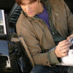 Jared Padalecki seduto nell'Impala mentre controlla le sue e-mail con il cellulare in 'la caccia ha inizio'
