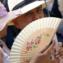 Un copricapo estivo per Berlusconi, seminascosto dietro il ventaglio di una signora.