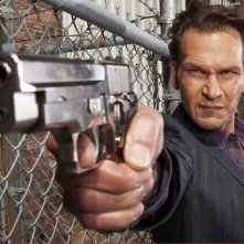 Patrick Swayze armato di pistola in una foto promozionale della serie The Beast