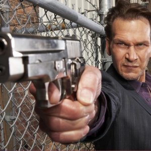 Patrick Swayze armato di pistola in una foto promozionale della serie The Beast