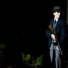 Christian Bale appostato dietro un albero in una concitata scena di Public Enemeies