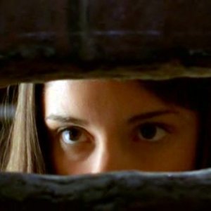 Liz Parker (S. Appleby) guarda attraverso un buco nel muro nell'episodio 'Il diario scomparso' di Roswell