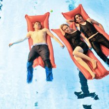 Rupert Grint, Kimberlye Nixon e Robert Sheehan sdraiati in piscina in una scena del film CherryBomb