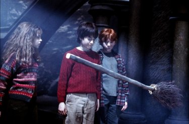 Emma Watson, Daniel Radcliffe e Rupert Grint osservano un manico scopa nel film Harry Potter and the Sorcerer's Stone