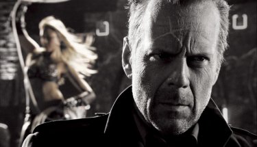 Un primo piano di Bruce Willis con alle spalle Jessica Alba in una scena di Sin City