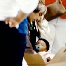 Sacha Baron Cohen nei panni di Bruno in una scena del film in cui ritira il suo bambino 'adottato' all'aeroporto