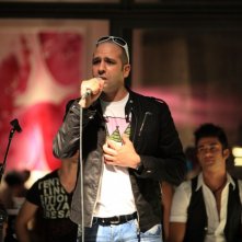 Checco Zalone (Luca Medici) al microfono nel film Cado dalle nubi