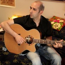 Checco Zalone (Luca Medici) con la chitarra nel film Cado dalle nubi