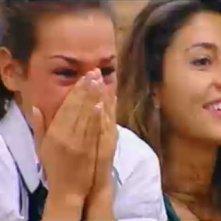 Grande Fratello 10, quarta puntata: Carmen riceve una sorpresa dal fratello. Dietro di lei, Camila sorride.