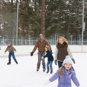 Bailee Madison, Jake Gyllenhaal, Natalie Portman e Taylor Geare pattinano, sorridenti, sul ghiaccio in una scena di Brothers