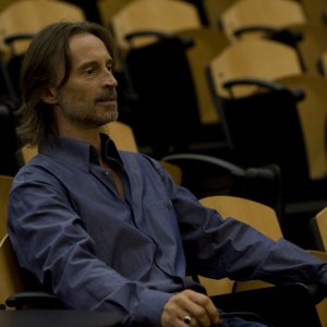 Rush (Robert Carlyle) seduto nella sua aula nell'episodio Human di Stargate Universe