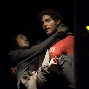 Eli (David Blue) porta in braccio Chloe (Elyse Levesque) in una scena dell'episodio Incursion: Part 2 di Stargate Universe