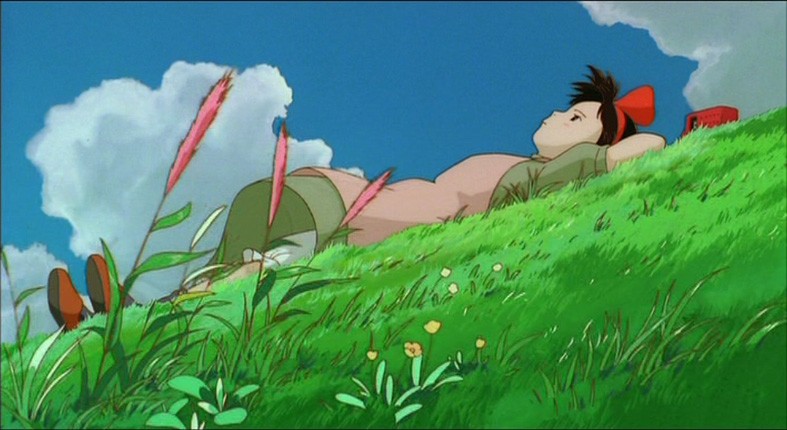 La piccola Kiki distesa su un prato in una scena del film d'animazione Kiki consegne a domicilio