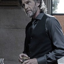 John Glover con bicchiere in mano in un momento dell'episodio Luthor di Smallville