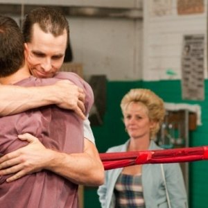 Mark Wahlberg e Christian Bale in un abbraccio fraterno con Melissa Leo sul fondo in The Fighter