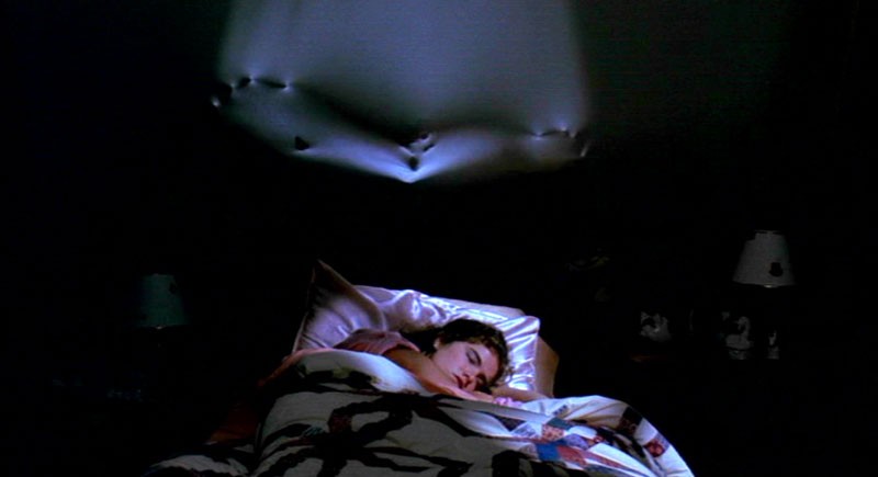 Heather Langenkamp dorme ignara sotto lo sguardo di Freddy Krueger in una scena di Nightmare - Dal profondo della notte