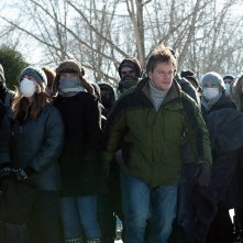 Matt Damon nel thriller Contagion insieme ad un gruppo di persone con il volto coperto