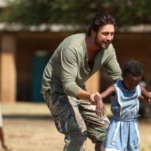 Gerard Butler nel film Machine Gun Preacher con una bimba di colore