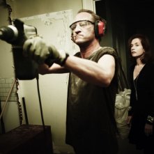 Benoît Poelvoorde alle prese con un trapano in una scena della commedia Mon pire cauchemar insieme a Isabelle Huppert