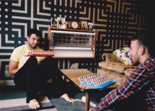 Tom Cullen e Chris New in una scena del dramma sentimentale Weekend alle prese con un gioco da tavolo