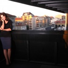 Il mio domani: un'elegante e cupa Claudia Gerini sul balcone parla al telefono in una scena dal film