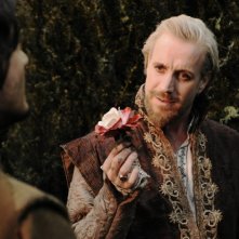 Rhys Ifans stringe tra le dita un fiore in una scena di Anonymous