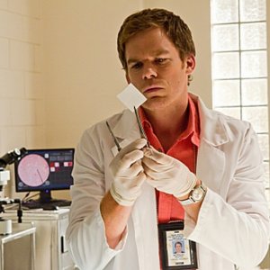 Michael C. Hall in laboratorio esamina un pezzo dell'ala dell'angelo in una scena dell'episodio The Angel of Death