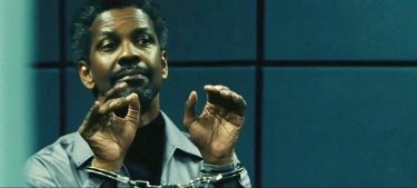 Denzel Washington sogghigna in manette una scena del thriller Safe House
