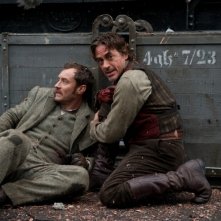 Jude Law e Robert Downey Jr. cercano di ripararsi dal pericolo in una scena di Sherlock Holmes: Gioco di ombre