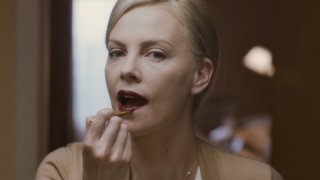 Charlize Theron si tinge le labbra in una scena del film Young Adult