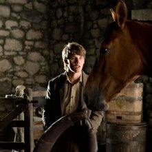 Jeremy Irvine nella stalla parla col suo cavallo in una scena di War Horse