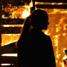 Sindi Laçej di spalle davanti alle fiamme in una scena del dramma La faida