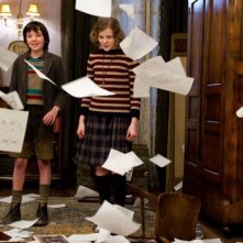 Asa Butterfield e Chloe Moretz tra fogli svolazzanti in un'immagine tratta da Hugo Cabret 3D