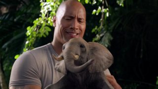 Dwayne Johnson stringe un piccolo elefante in una scena di Viaggio nell'isola misteriosa