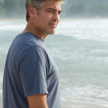 George Clooney in spiaggia scruta l'orizzonte in una scena del film Paradiso amaro