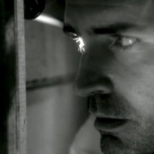 Jason Patric spia dal buco di una serratura in una scena del thriller Keyhole