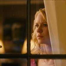 Naomi Watts sospettosa dietro una finestra in una scena di Dream House