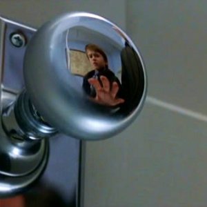 Haley Joel Osment riflesso nella maniglia di una porta in una sequenza de Il sesto senso