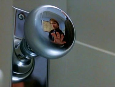 Haley Joel Osment riflesso nella maniglia di una porta in una sequenza de Il sesto senso