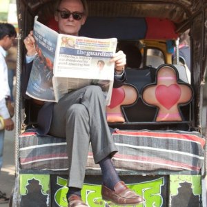 Marigold Hotel: Bill Nighy in una scena del film legge The Guardian a bordo dei una carrozzella indiana