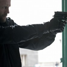 Killer Elite: Jason Statham punta la sua arma in una scena dell'action movie