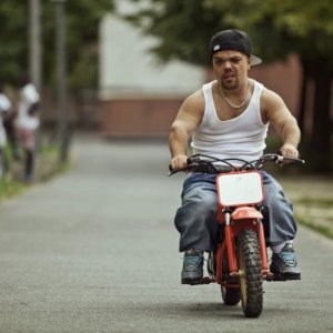 Jib Pocthier in sella ad una piccola motocicletta in Les Kaïra