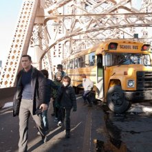 Joseph Gordon-Levitt circondato dai bambini di uno scuolabus in una scena di Il cavaliere oscuro - Il ritorno