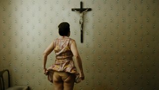 Paradise: Faith, la protagonista del film Maria Hofstätter di spalle guarda un crocefisso in una scena del film