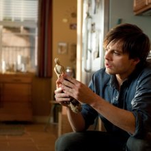 Sebastian Stan osserva un manufatto nel film The Apparition