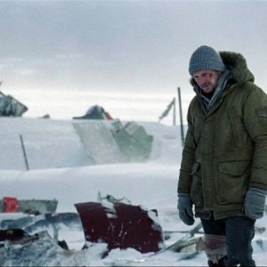 Liam Neeson distrutto di fronte al relitto del suo aereo in una scena di The Grey