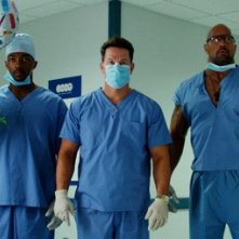 Anthony Mackie, Mark Wahlberg e Dwayne Johnson vestiti da medici in una scena di Suda e cresci